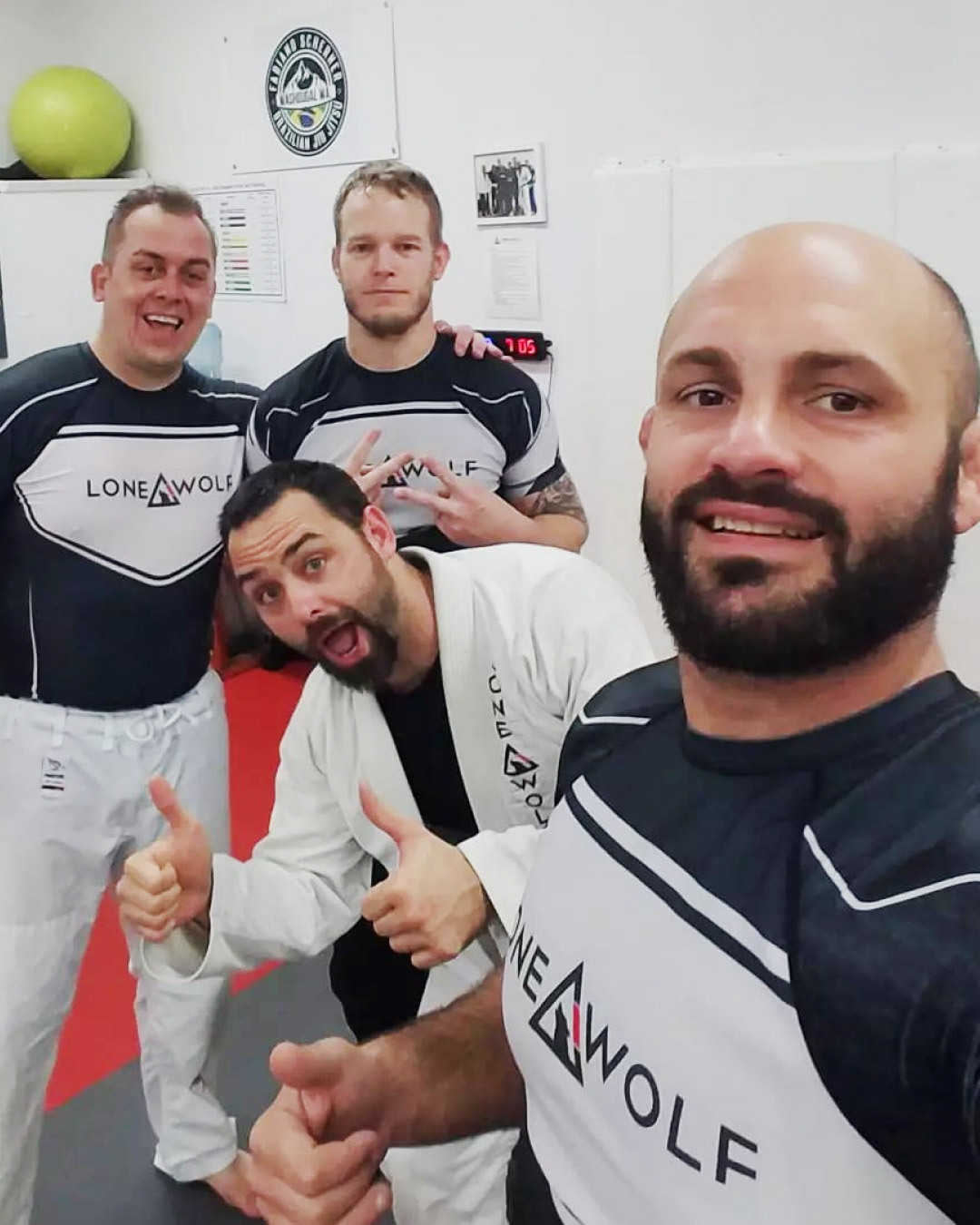 Don Stoner posing with students at his school. They are all wearing black and white Lone Wolf Jiu-Jitsu rash guards and white gi pants.