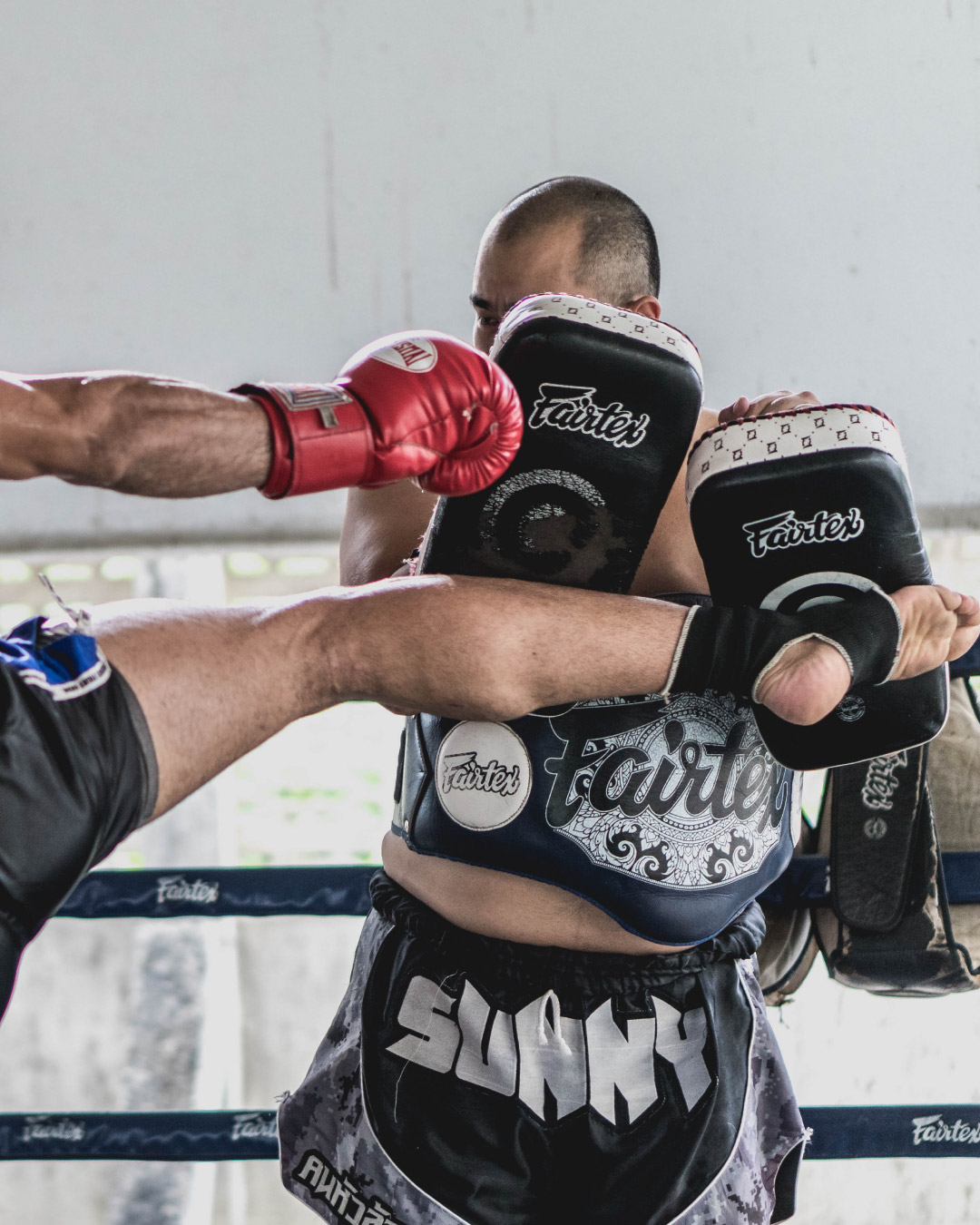 A man kicks a pair of striking mitts.
