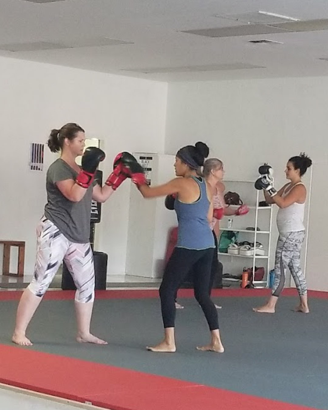 A group of women practice fitness kickboxing at Lone Wolf Jiu-Jitsu with each other taking turns throwing different combos.